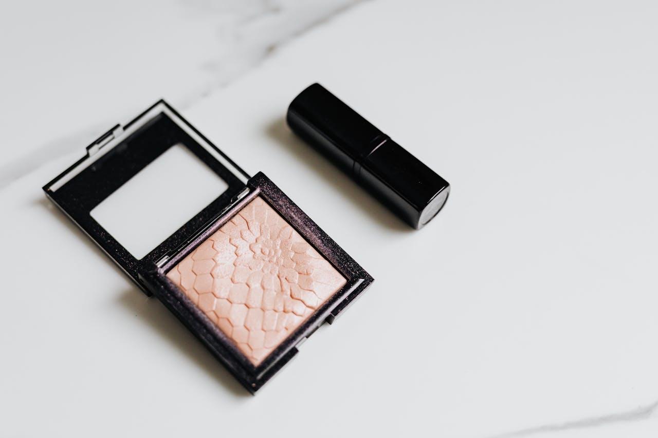 A minimalist still life featuring blush and lipstick on a clean white background for beauty and cosmetics themes.